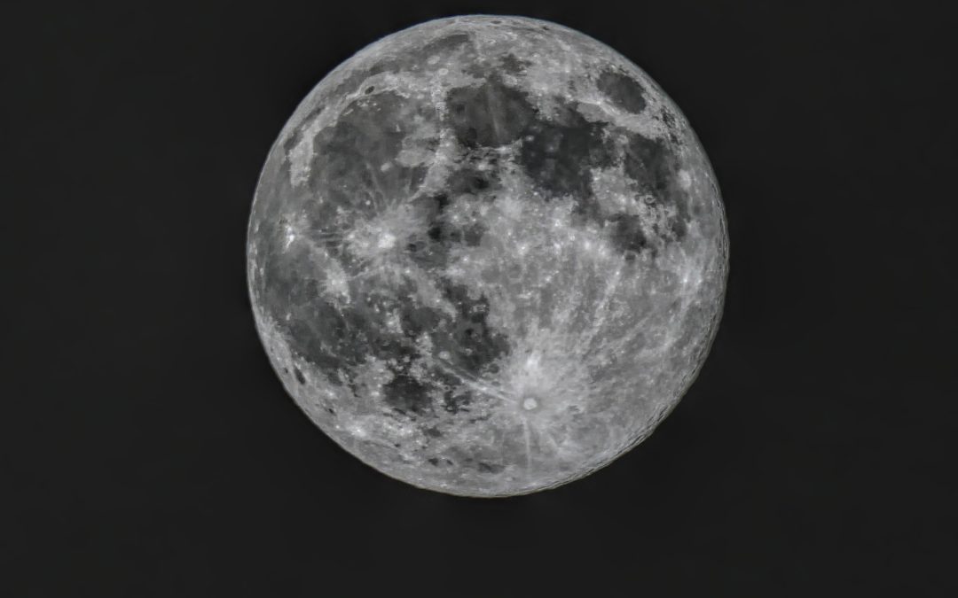 Das Bild zeigt eine klare, stark vergrößerte Aufnahme des Vollmonds vor tiefschwarzem Nachthimmel. Die Mondoberfläche ist deutlich und kontrastreich zu sehen: typische helle und dunkle Strukturen, die sogenannten Mondmeere (Mare) und Krater, sind gut erkennbar. Besonders sichtbar sind die großen, dunkleren Flächen sowie helle Strahlenkrater, deren Auswurfspuren sternförmig vom Einschlagspunkt ausgehen. Der Mond wirkt nahezu rund und nimmt einen Großteil des Bildes ein; es gibt keine anderen Objekte oder Sterne im Hintergrund. Die Aufnahme wirkt ruhig, detailreich und vermittelt den Eindruck, als würde man durch ein Teleskop blicken.